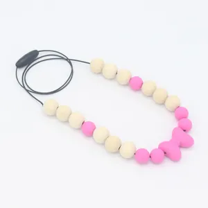 Détail du collier de dentition bébé avec nœud en silicone rose et perles en bois naturel