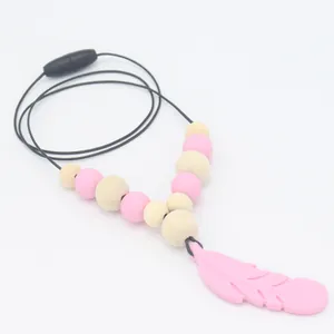 Gros plan du pendentif plume en silicone rose avec perles en bois pour collier de dentition