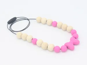 Détail du pendentif nœud en silicone rose avec perles en bois et fermoir de sécurité enfant