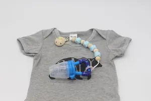 Grignoteuse bébé en silicone bleue avec attache-tétine perlée sur un body gris