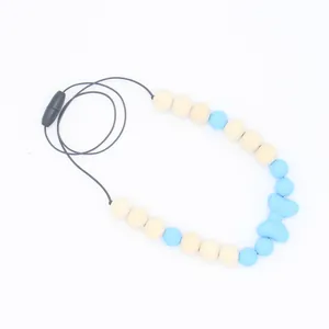 Vue détaillée du collier de dentition pour bébé avec nœud en silicone bleu, perles en bois et fermoir