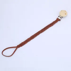 Détail de l'attache-tétine tressée en daim marron avec clip rond en bois naturel
