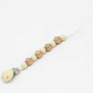 Détail de l'attache-tétine en bois avec perles naturelles et perles hexagonales dorées