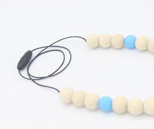 Détail du collier de dentition avec perles en bois naturel, silicone bleu et fermoir sûr