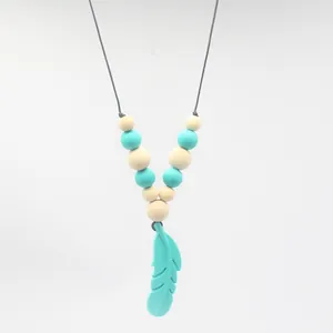 Gros plan sur le pendentif plume en silicone et les perles du collier de dentition
