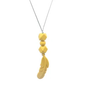Close-up of yellow silicone feather pendant and geometric beads on a soft teething necklace