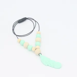 Détail du collier de dentition en silicone avec plume vert menthe et perles en bois