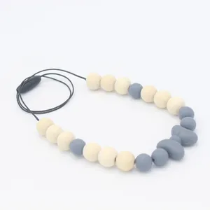 Détail du collier de dentition pour bébé avec nœud en silicone gris et perles en bois naturel