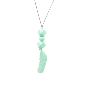 Detailed macro view of mint green silicone feather teether pendant with geometric beads