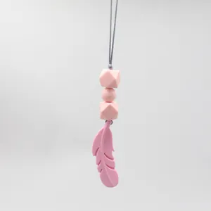 Detail of pink silicone feather teething necklace with hexagonal sensory beads for baby