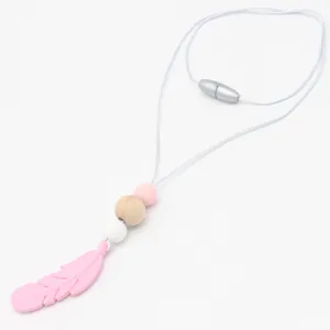 Detail van roze siliconen bijtketting met veer en natuurlijke beukenhouten kralen