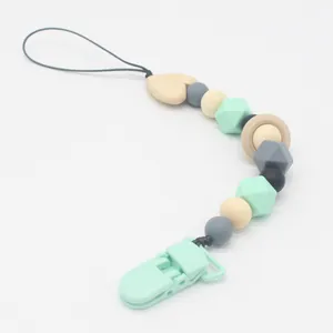 Detail of baby pacifier clip featuring mint silicone beads and natural wooden ring