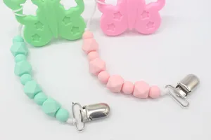 Detalle de sujetachupetes de silicona con dijes de mariposa en rosa y verde menta