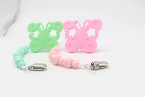 Detalle de chupeteros de silicona con mordedor de mariposa en colores rosa y verde menta