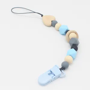 Detail of silicone and wood baby pacifier clip with heart accent and blue plastic clamp