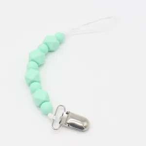 Detalle de cuentas de silicona verde menta y clip de metal en la cadena del chupete