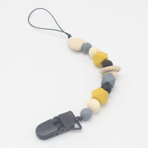 Detail of baby pacifier clip with wood and silicone beads in grey and yellow tones