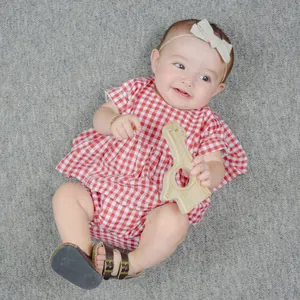 Infant red plaid romper set with bow headband, leather sandals and wooden giraffe teether