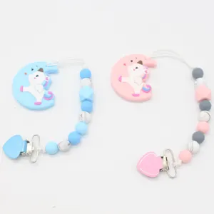 Detail of pink and blue silicone pacifier clips with unicorn pendants and heart-shaped clips