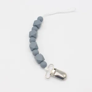 Detalle del sujetachupete de silicona gris con clip de metal plateado para bebés en dentición
