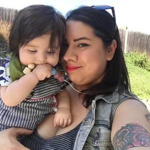 Baby met een groene slabbetje en kleurrijke siliconen bijtketting buiten spelend