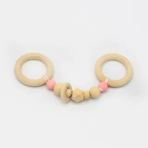 Détail d'un hochet bébé en bois de hêtre avec perles en silicone rose et anneaux naturels