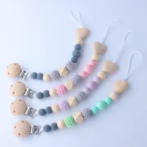 Detail view of colorful silicone and beech wood baby pacifier clips in macaron colors