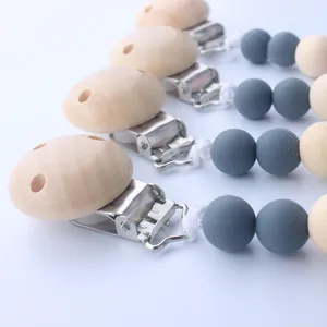 Detail view of silicone and beech wood baby pacifier clips with stainless steel fasteners