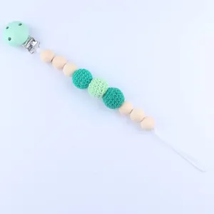 Baby speenketting met mintgroene gehaakte kralen en houten kralen op blauwe achtergrond
