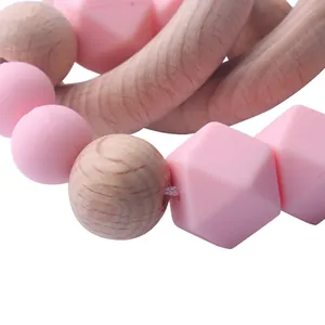 Baby teething bracelet made of natural beech wood and pink silicone beads on white background