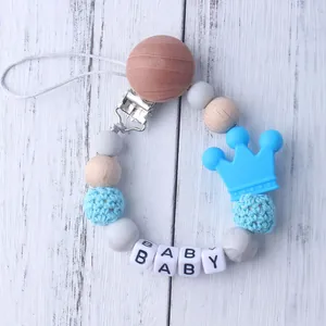 Detail of baby pacifier clip with silicone crown, blue crochet beads, and BABY letter beads