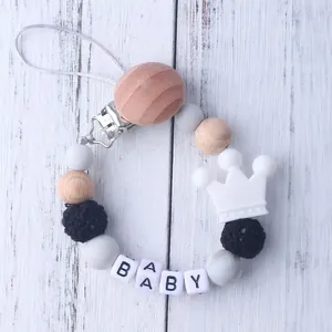 Detail of silicone pacifier clip with wood beads and white crown charm for baby