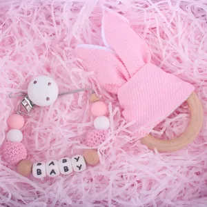 Detailaufnahme von Schnullerkette mit Beißring aus Holz in einer rosa Geschenkbox