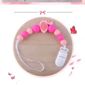 Nahaufnahme der Silikon-Schnullerkette mit rosa Flamingo auf hellem Holzgrund
