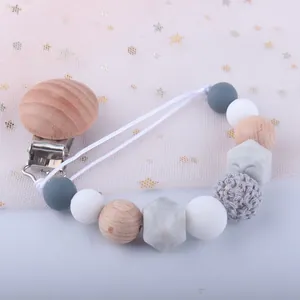 Attache-tétine en silicone et bois avec perles de marbre gris sur fond de tulle décoratif