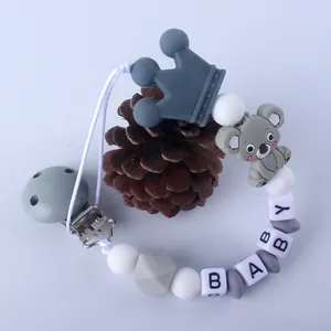 Detalle del sujetachupetes de silicona con koala gris, corona y cuentas con letras BABY
