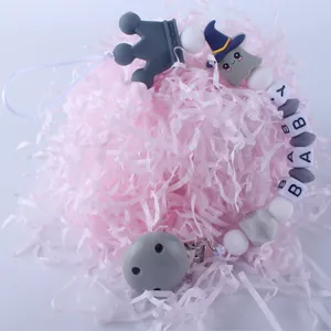 Detalle del sujetachupetes de silicona con fantasma, corona y letras BABY en fondo rosa