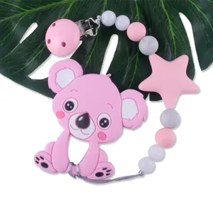 Chupetero de koala rosa con cuentas de silicona sobre una hoja verde natural