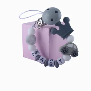 Detalle de sujetachupetes de silicona con dijes de corona, coche gris y cuentas BABY