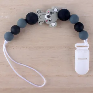 Detailaufnahme der Silikon-Schnullerkette mit grauem Koala und Perlen auf Holzdekor