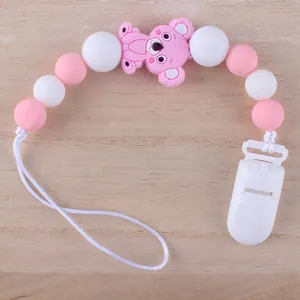 Detail der Baby-Schnullerkette mit rosa Silikon-Koala und lebensmittelechten Perlen auf Holz