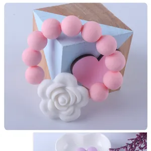 Anello da dentizione in silicone rosa con fiore di rosa 3D su sfondo blu tenue