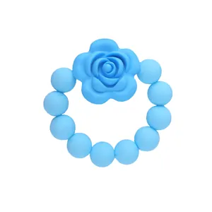 Dettaglio di un anello da dentizione in silicone celeste con perline e un fiore di rosa