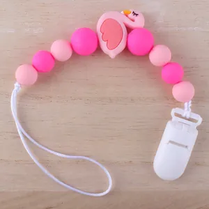 Rosa Silikon Schnullerkette mit Flamingo Perlen auf hellem Holzhintergrund