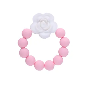 Dettaglio macro di perle per dentizione in silicone rosa con accento di rosa bianca