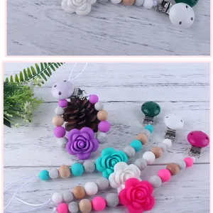 Detail of four colorful silicone pacifier clips with floral beads and wooden accents