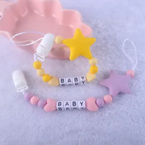 Baby pacifier clip set with silicone beads and star charms on a soft plush background