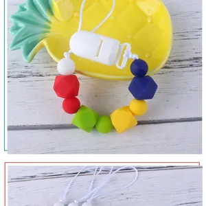 Close-up of colorful silicone baby pacifier clip beads on a pineapple tray