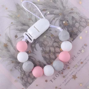 Catenella portaciuccio in silicone con perle rosa e grigie su sfondo di piante tropicali