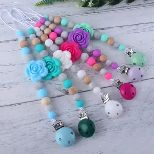 5-pack silicone baby pacifier clips with wood beads and flower charms on white wood background